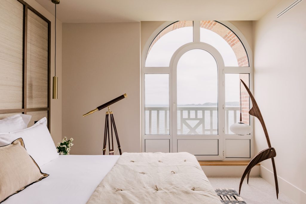 Chambre de l’hôtel Les Bassans avec lit, fauteuil design, télescope et vue mer