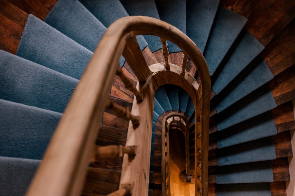 Escalier en bois avec moquette bleue dans l’hôtel Les Bassans à Perros-Guirec