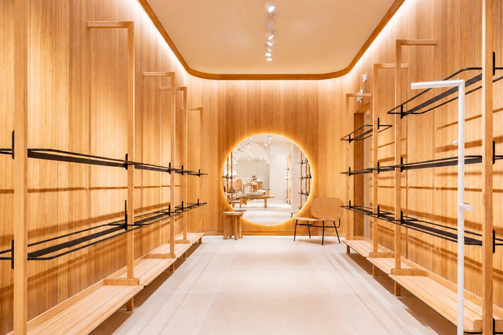 Boutique Mango Caen New Med avec revêtements bois, portants vêtements noirs et miroir rond lumineux