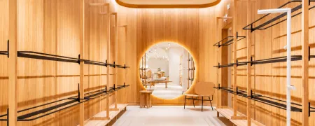 Boutique Mango Caen New Med avec revêtements bois, portants vêtements noirs et miroir rond lumineux