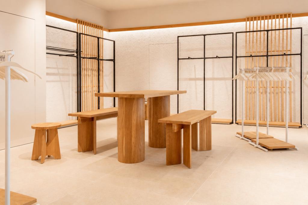 Mobilier central en bois dans la boutique Mango Caen New Med avec portants et revêtements muraux clairs