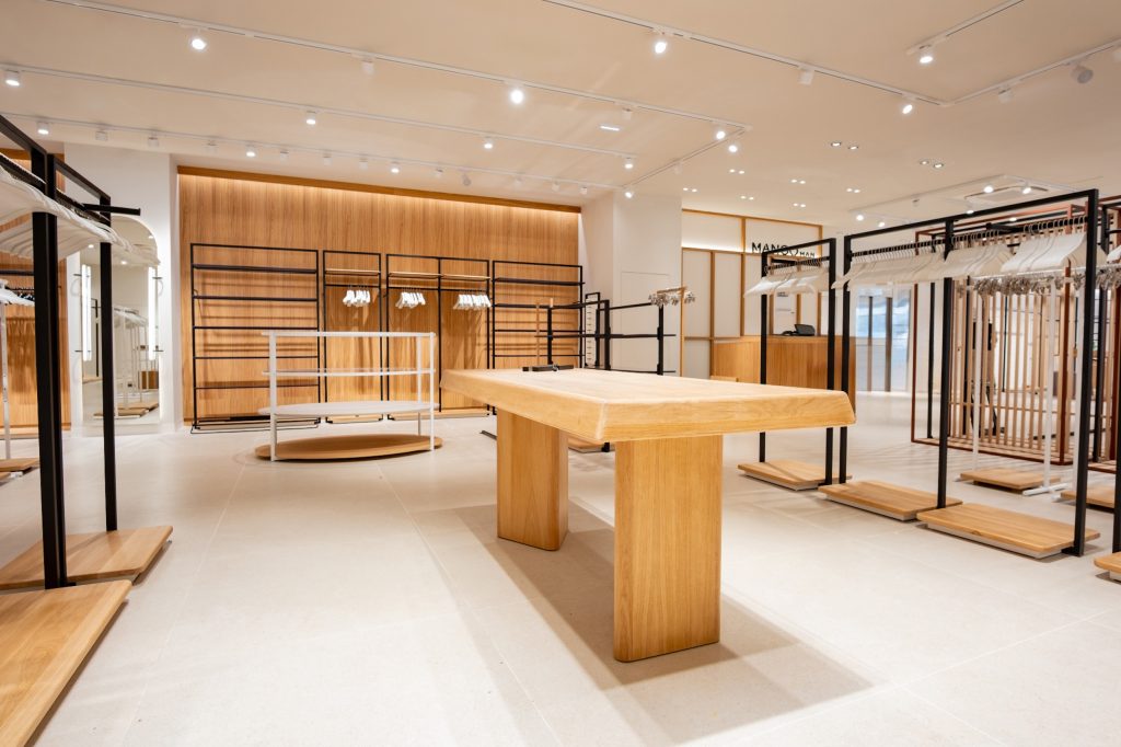 Espace de vente Mango Caen New Med avec table centrale bois, portants vêtements et éclairage retail