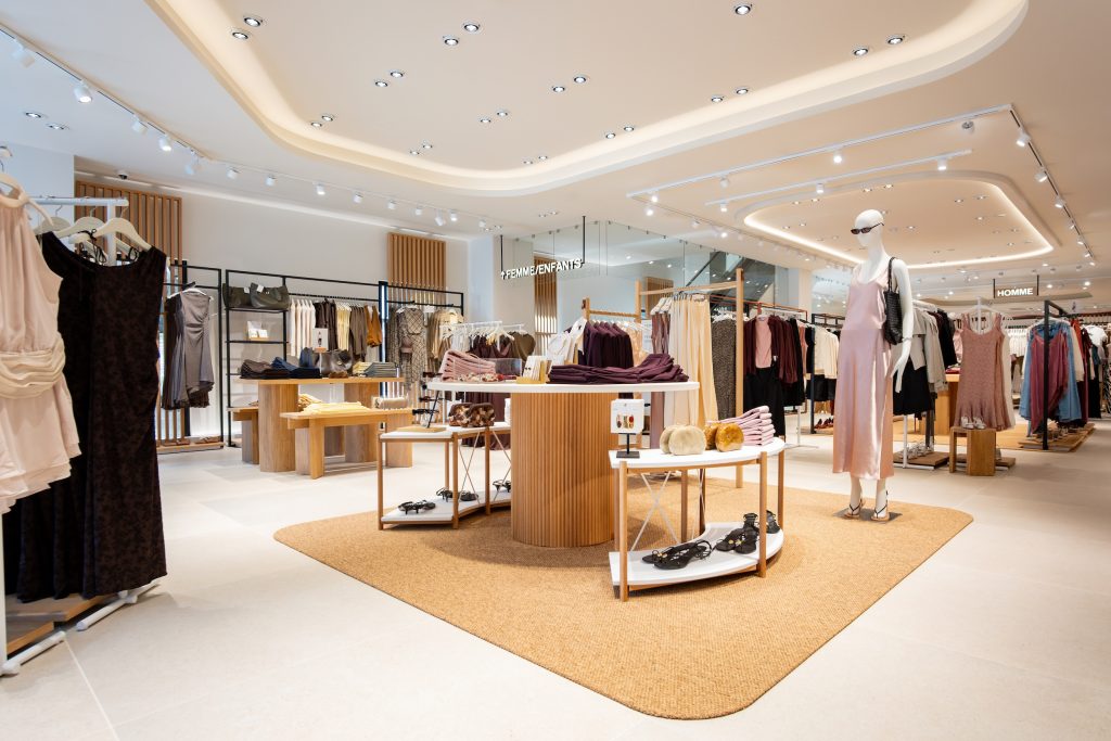 Espace femme de la boutique Mango Caen avec table centrale, mannequins, portants et mobilier bois