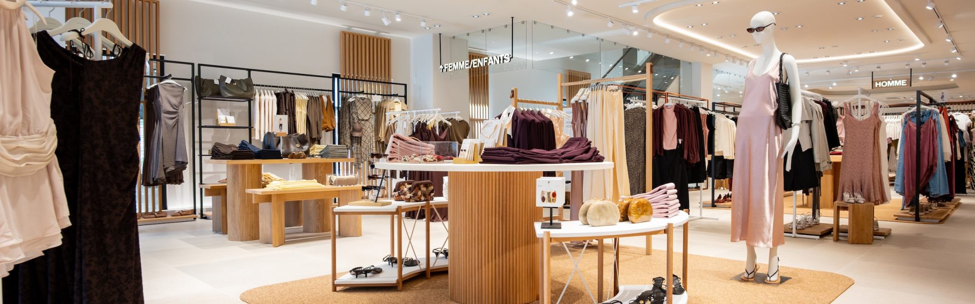 Espace femme de la boutique Mango Caen avec table centrale, mannequins, portants et mobilier bois