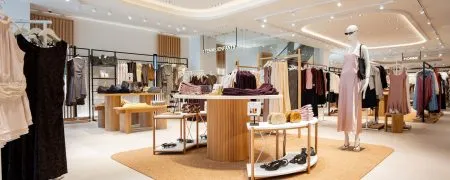 Espace femme de la boutique Mango Caen avec table centrale, mannequins, portants et mobilier bois