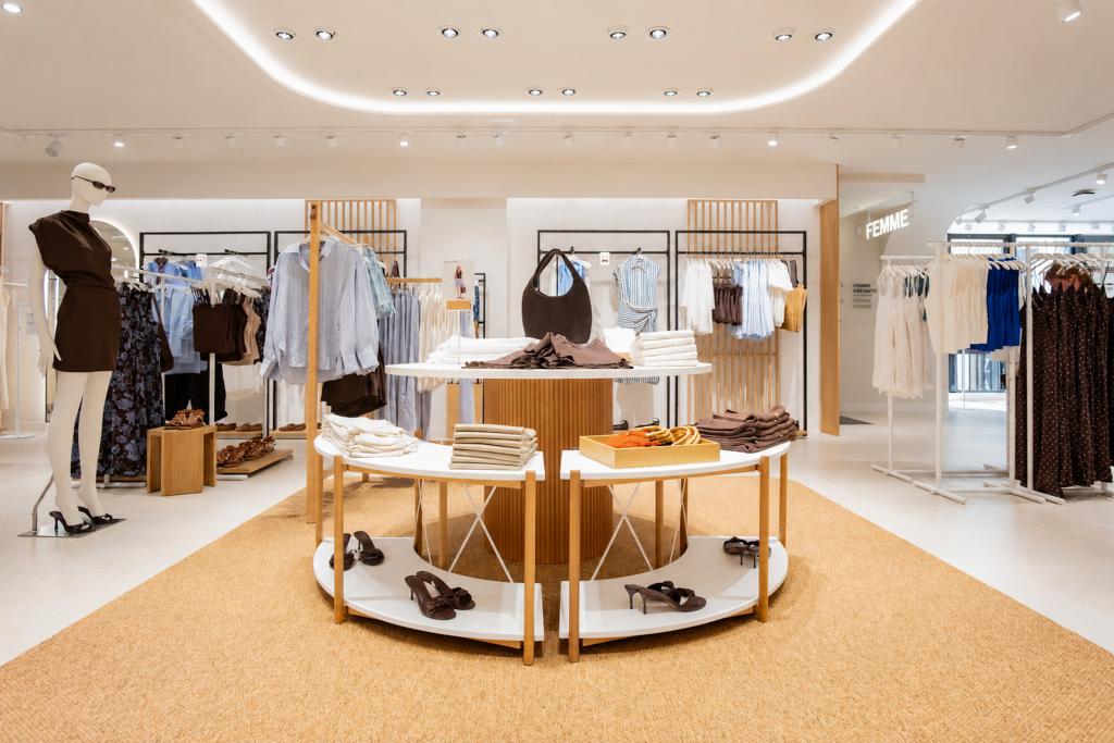Vue verticale de la boutique Mango Caen avec plafond lumineux arrondi, table centrale et portants vêtements
