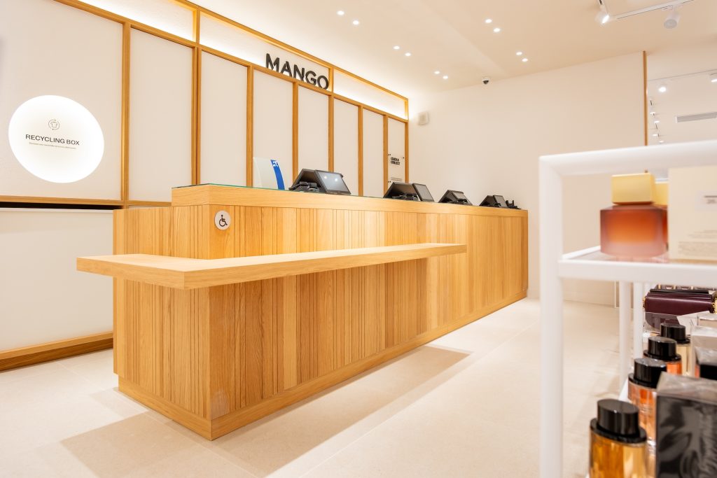 Comptoir caisse en bois de la boutique Mango Caen avec logo mural, postes d’encaissement et accessibilité PMR
