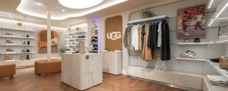Boutique UGG Le Marais à Paris avec mobilier clair, plafond courbe lumineux, portants vêtements et espace chaussures