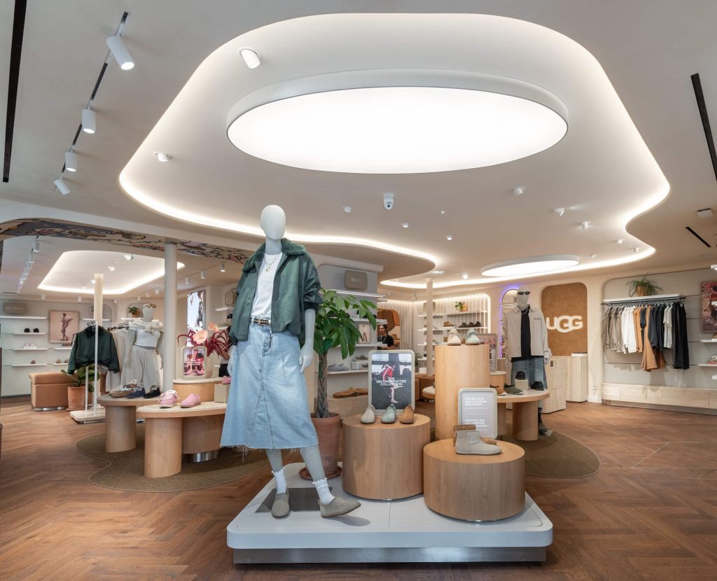 Intérieur de la boutique UGG Le Marais avec mannequin, mobilier central, plafond lumineux et logo mural