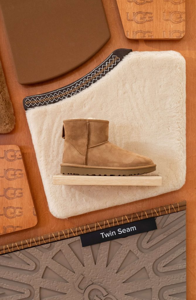 Botte UGG exposée sur un support bois avec matière fourrée et panneau produit dans la boutique du Marais à Paris