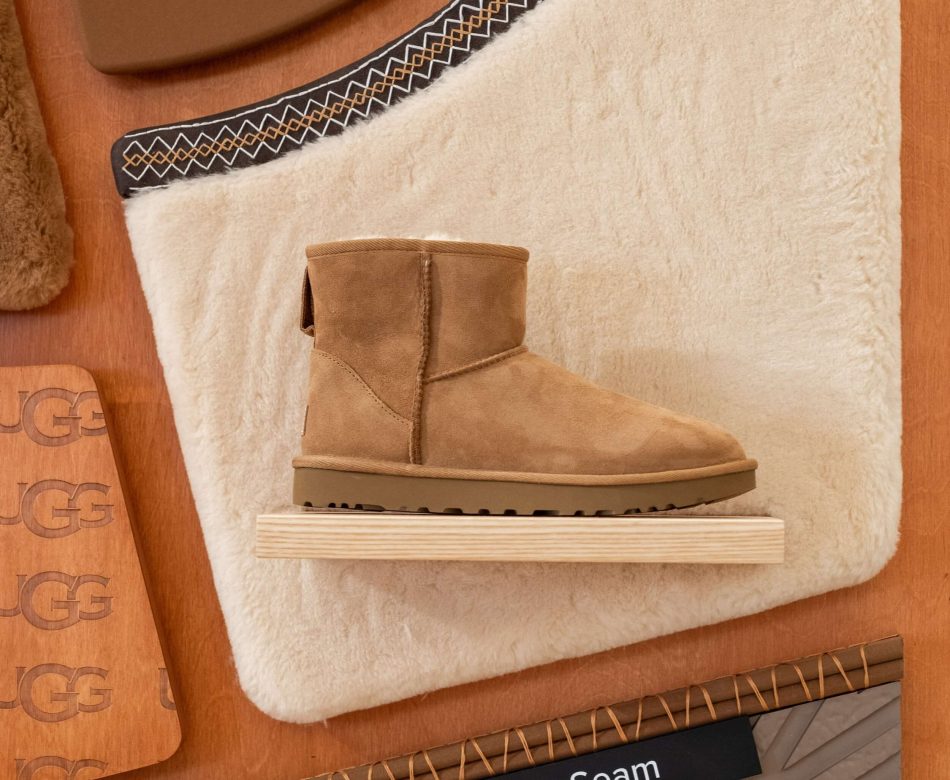 Botte UGG exposée sur un support bois avec matière fourrée et panneau produit dans la boutique du Marais à Paris