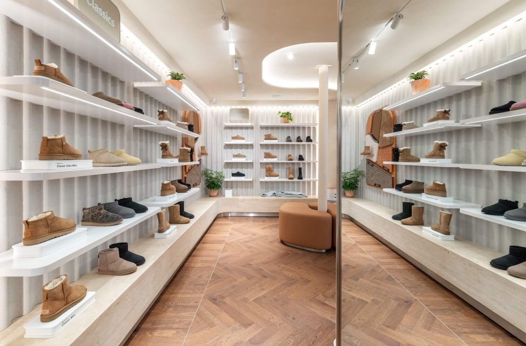 Linéaire chaussures dans la boutique UGG Le Marais avec étagères rétroéclairées, parquet en chevrons et assise centrale