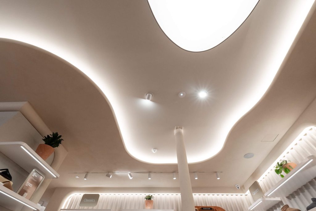 Plafond courbe avec gorge lumineuse intégrée dans la boutique UGG Le Marais à Paris