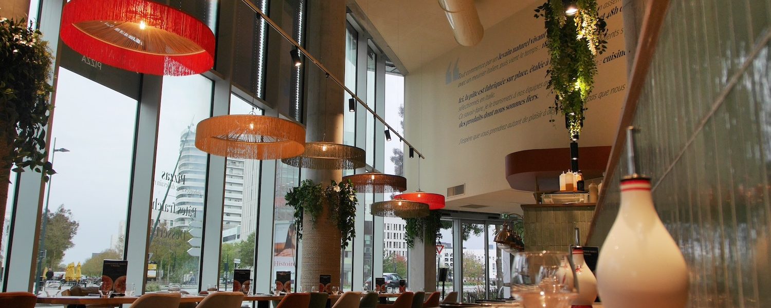 Aménagement intérieur du restaurant Jordan Tomas Pizza à Nantes avec grandes baies vitrées et suspensions décoratives