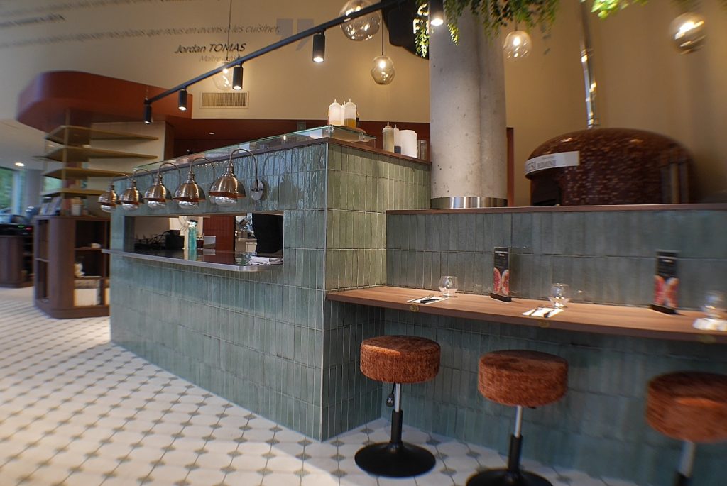 Comptoir en carrelage vert et mange-debout intégrés à l'agencement du restaurant Jordan Tomas Pizza à Nantes