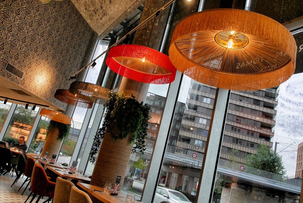 Suspensions en rotin colorées et grandes baies vitrées du restaurant Jordan Tomas Pizza à Nantes